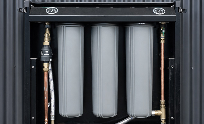 Puretec whole house filtration cartridges inside a FilterWall cabinet with the cover open