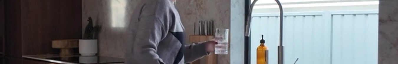 Pouring a glass of filtered water in the kitchen of an 8 star sustainable home